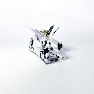 A large black and white marbled hair claw clip is presented against a white background.